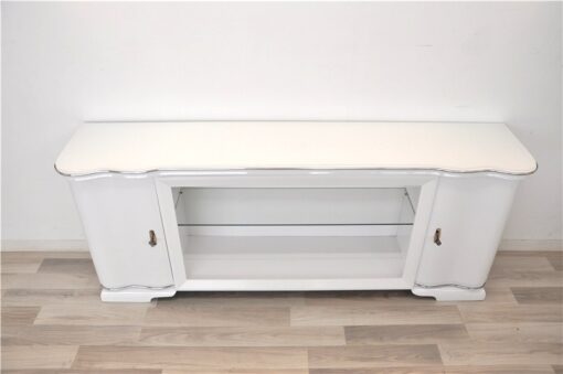 Art Deco Lowboard, lacquer in highgloss white, curved doors in a classic design, glass shelve in the middle compartement, chromelines