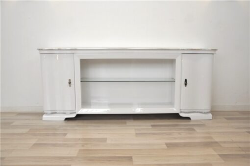 Art Deco Lowboard, lacquer in highgloss white, curved doors in a classic design, glass shelve in the middle compartement, chromelines